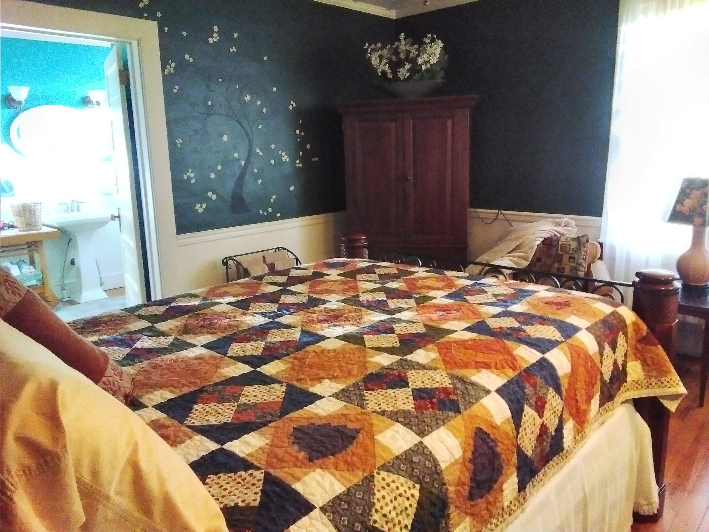 A bedroom with a large bed, a wooden wardrobe, a nightstand, and a window with curtains.