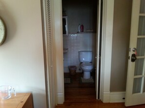 Een smalle gang die leidt naar een badkamer met een toilet en een prullenbak.