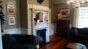 A living room with a fireplace, two sofas, a coffee table, and a chandelier. - Hunter House Bed and Breakfast (Madison)
