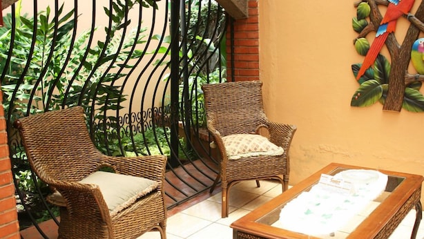 A balcony with wicker chairs and a glass-top table. - Hotel Millenium (Rio Segundo)