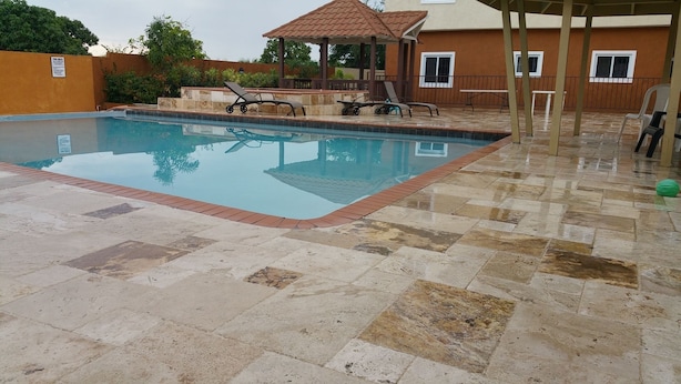 Una piscina con sillas de descanso y un pabellón.