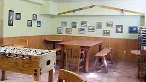 Una habitación con una mesa de fútbol de mesa, sillas de madera y una mesa pequeña.