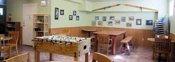 Una habitación con una mesa de fútbol de mesa, sillas de madera y una mesa pequeña.