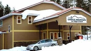 Un edificio de dos pisos con un letrero que dice "Castle Mountain Ski Lodge & Hotel".