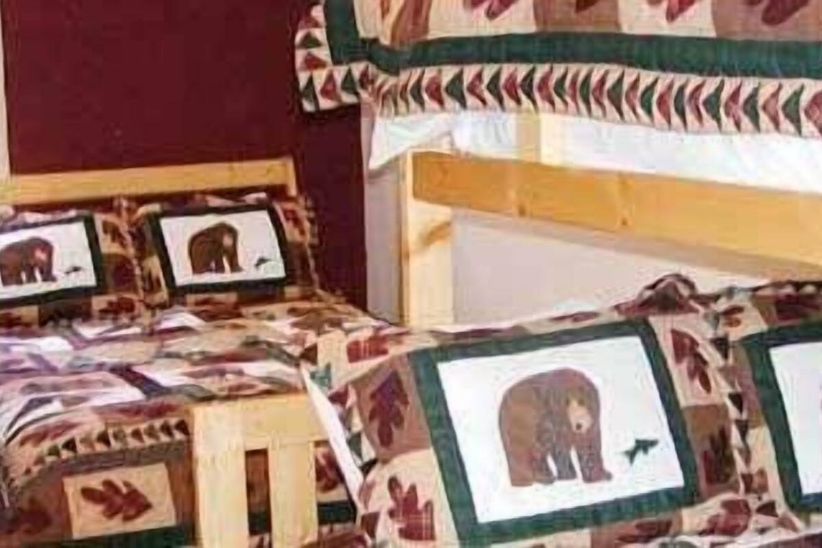 Habitación con una cama, colcha estampada de animales y fotografías enmarcadas.