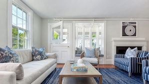 A living room with a sofa, armchairs, a coffee table, and a fireplace. - Martin House Inn (Nantucket)