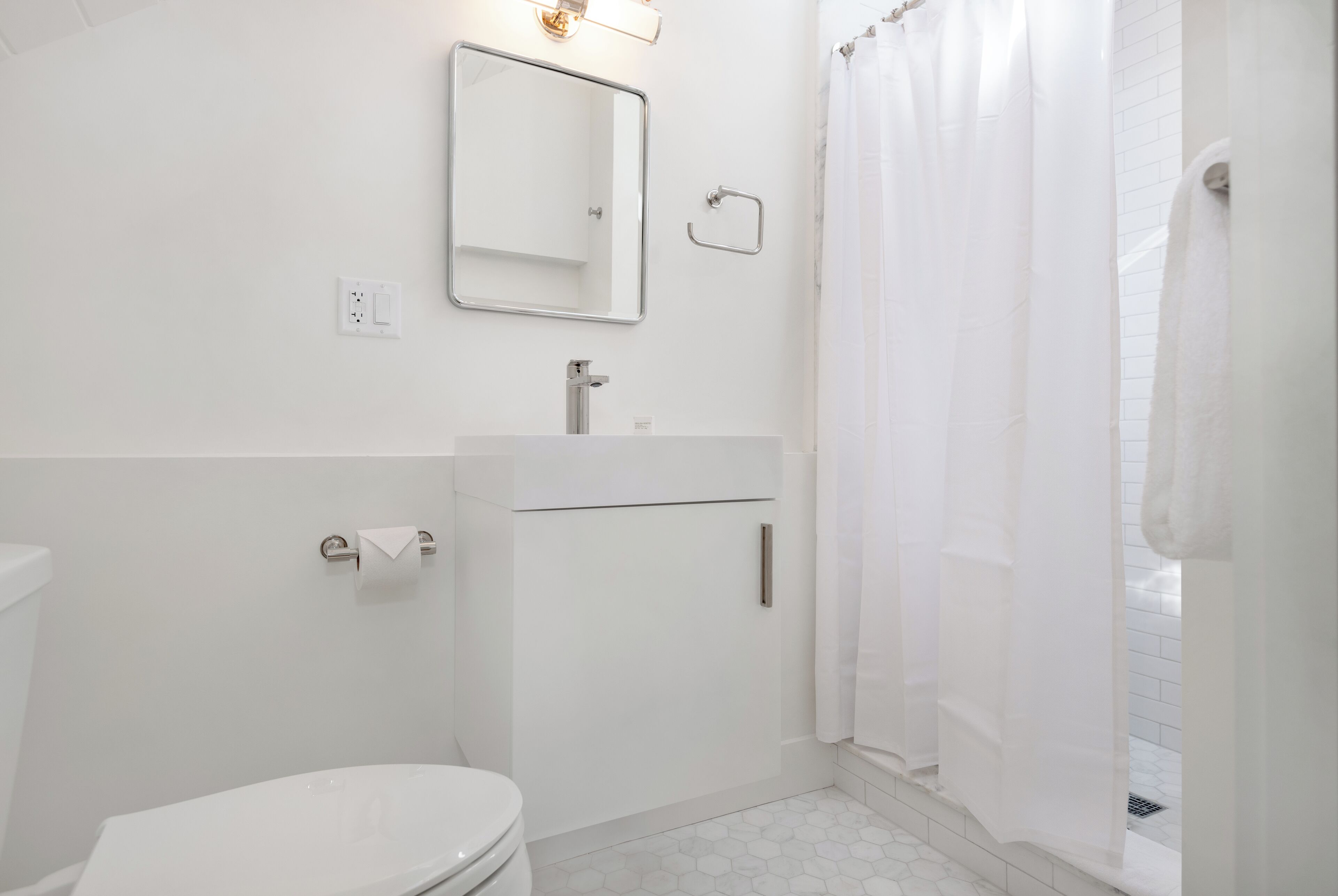 Un baño moderno con inodoro, lavamanos y cortina de ducha.