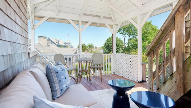 A covered outdoor seating area with a wooden deck, a white gazebo, and a view of a building in the background. - Martin House Inn (Nantucket)