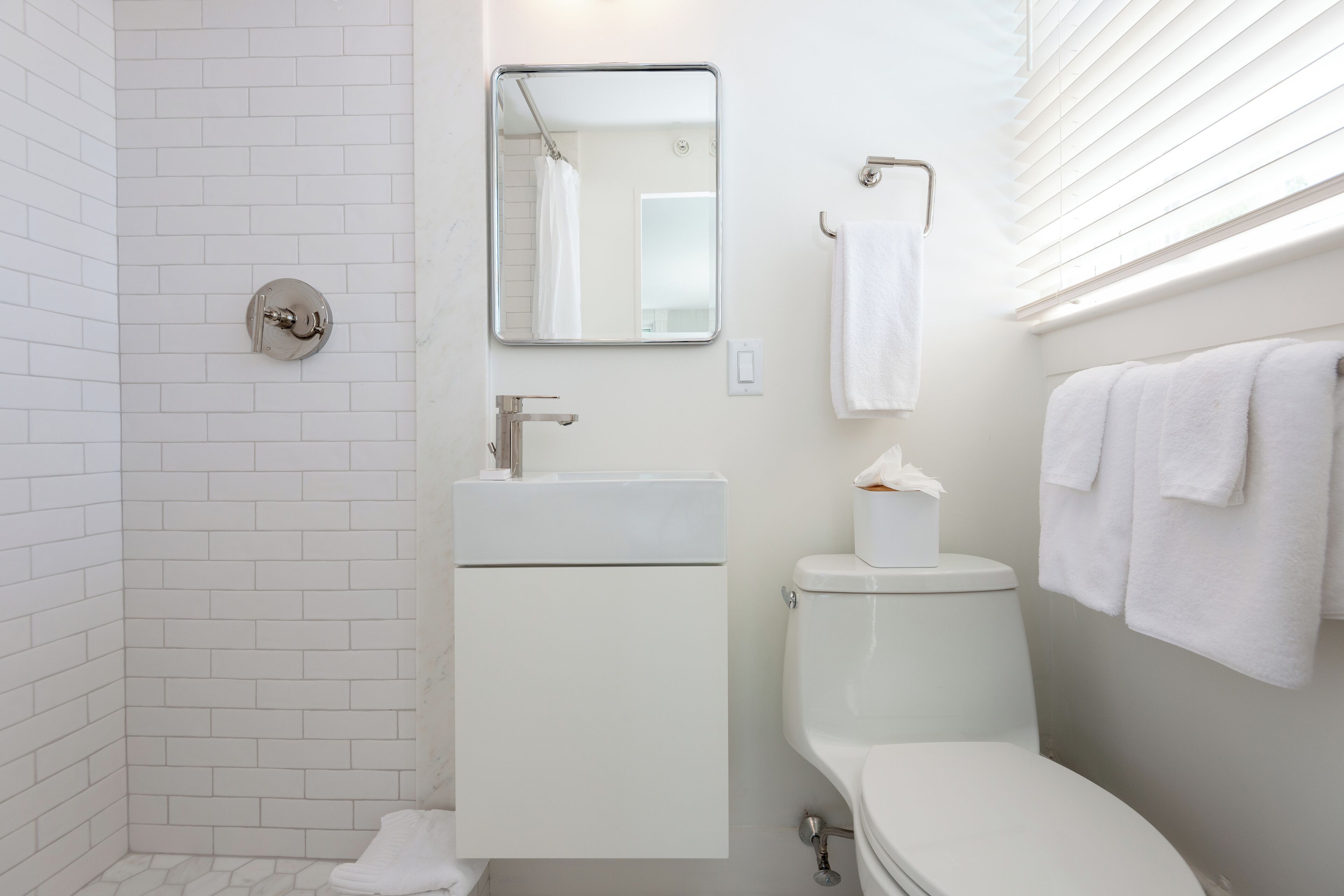 Une salle de bain moderne avec un lavabo, des toilettes et une douche, le tout de couleur blanche.