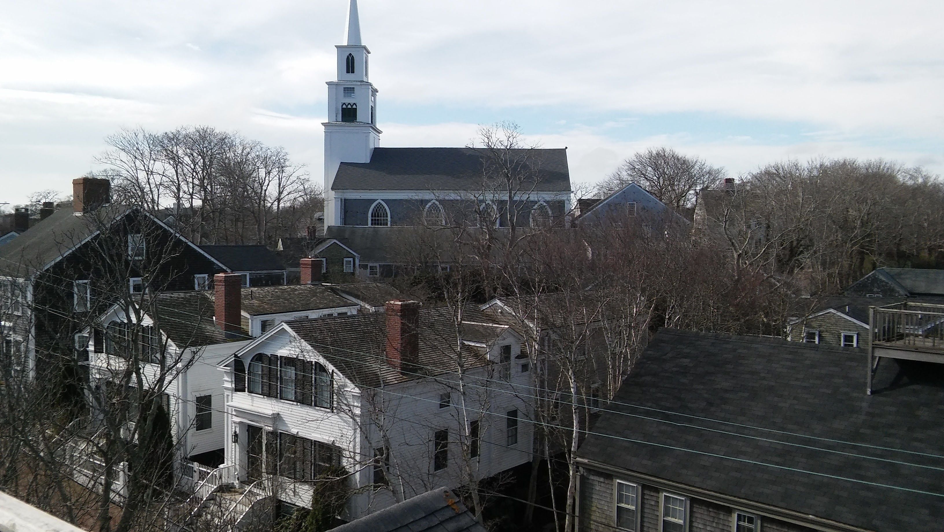 Une église dotée d’un clocher et d’un beffroi, entourée d’immeubles d’habitation.