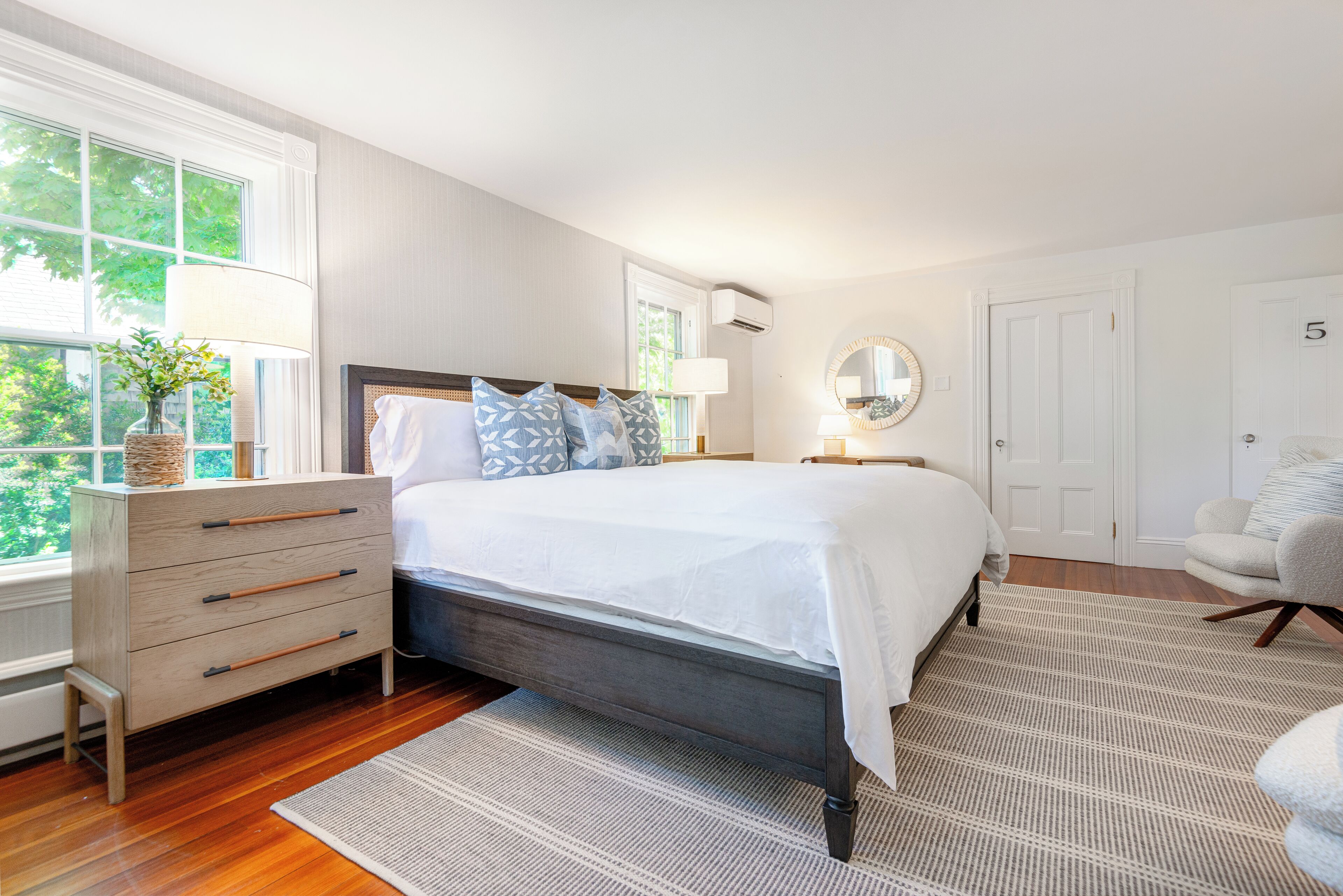 Une chambre à coucher avec un lit, une commode et une fenêtre donnant sur un paysage verdoyant.