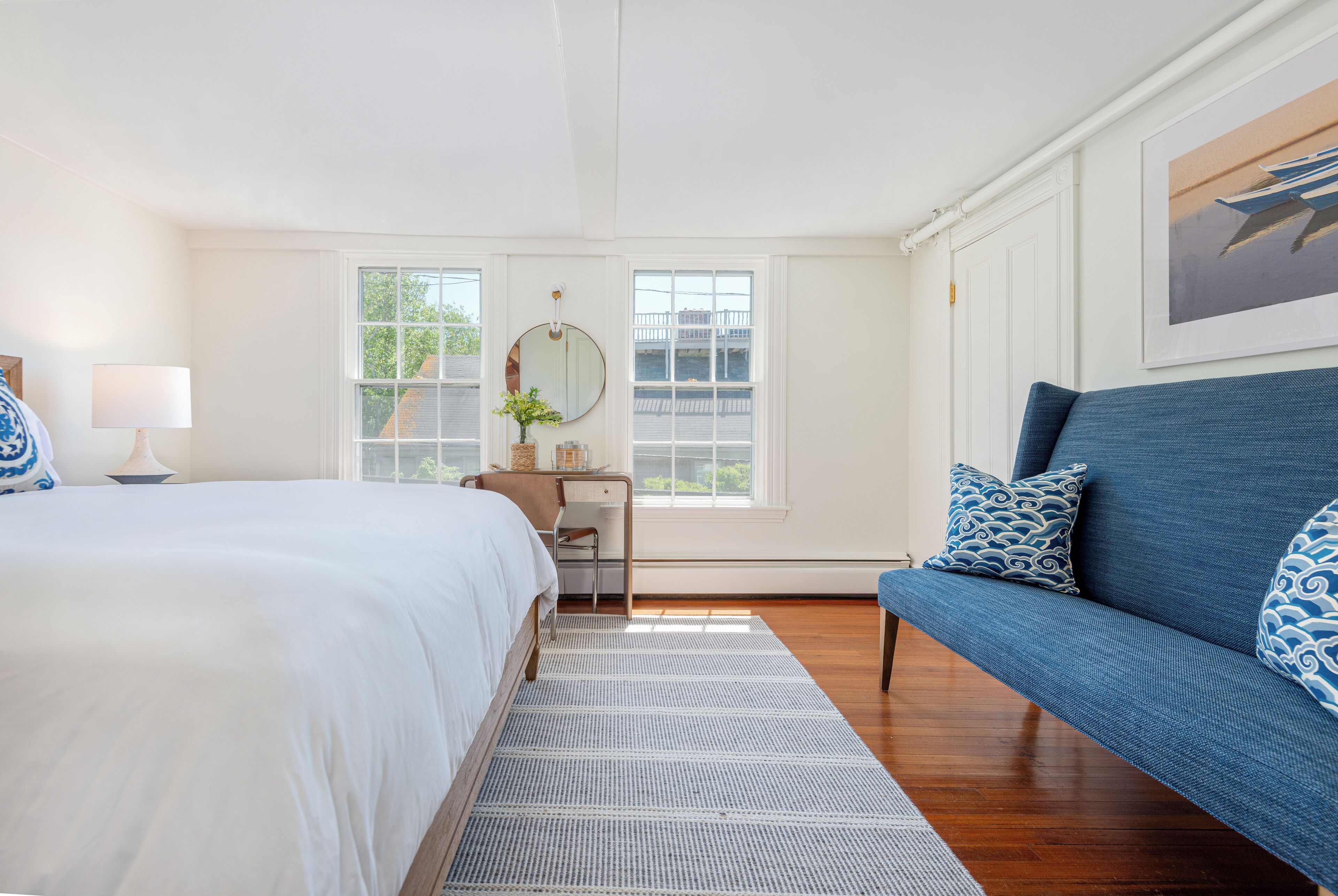 Un dormitorio con cama, escritorio, silla, sofá y ventana.