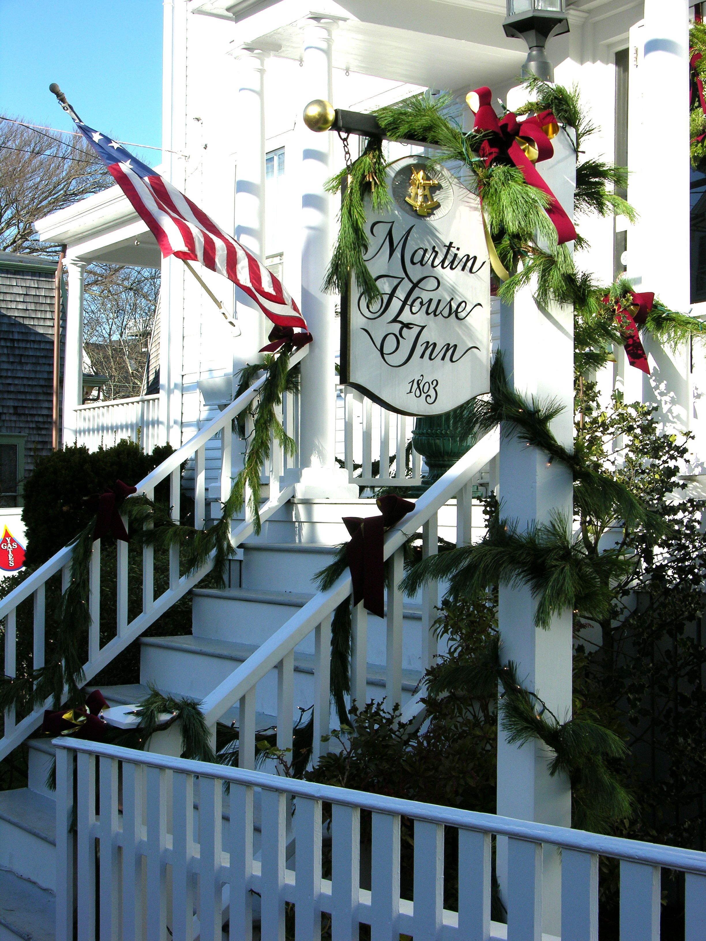 Una escalera con un cartel para Martin House Inn, decorada con ramas de hoja perenne y cintas.