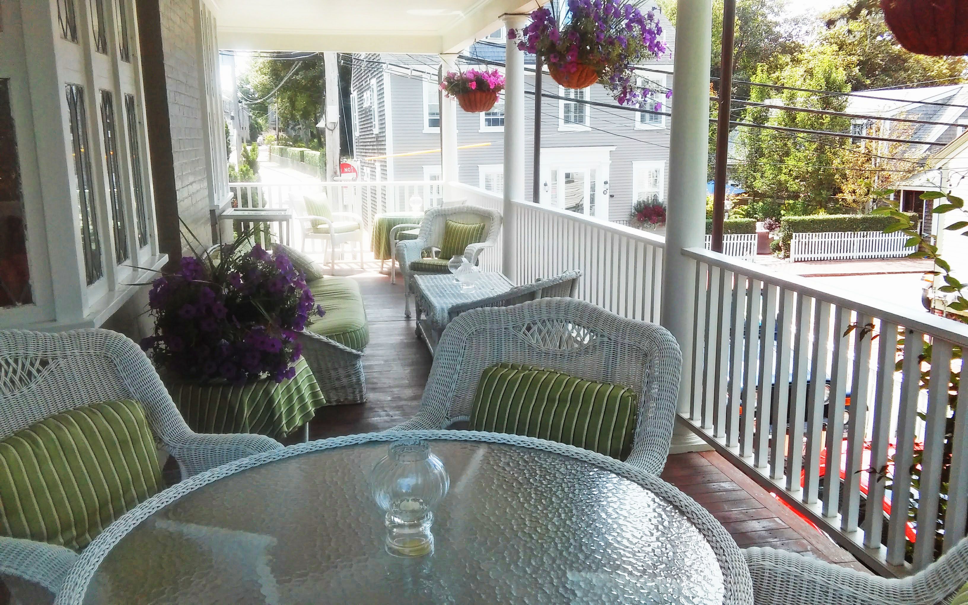 A covered outdoor seating area with wicker furniture and hanging flower baskets.