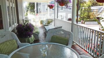 A covered outdoor seating area with wicker furniture and hanging flower baskets.