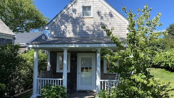 A single-story house with a gabled roof, a front porch with white railings, and a front door.