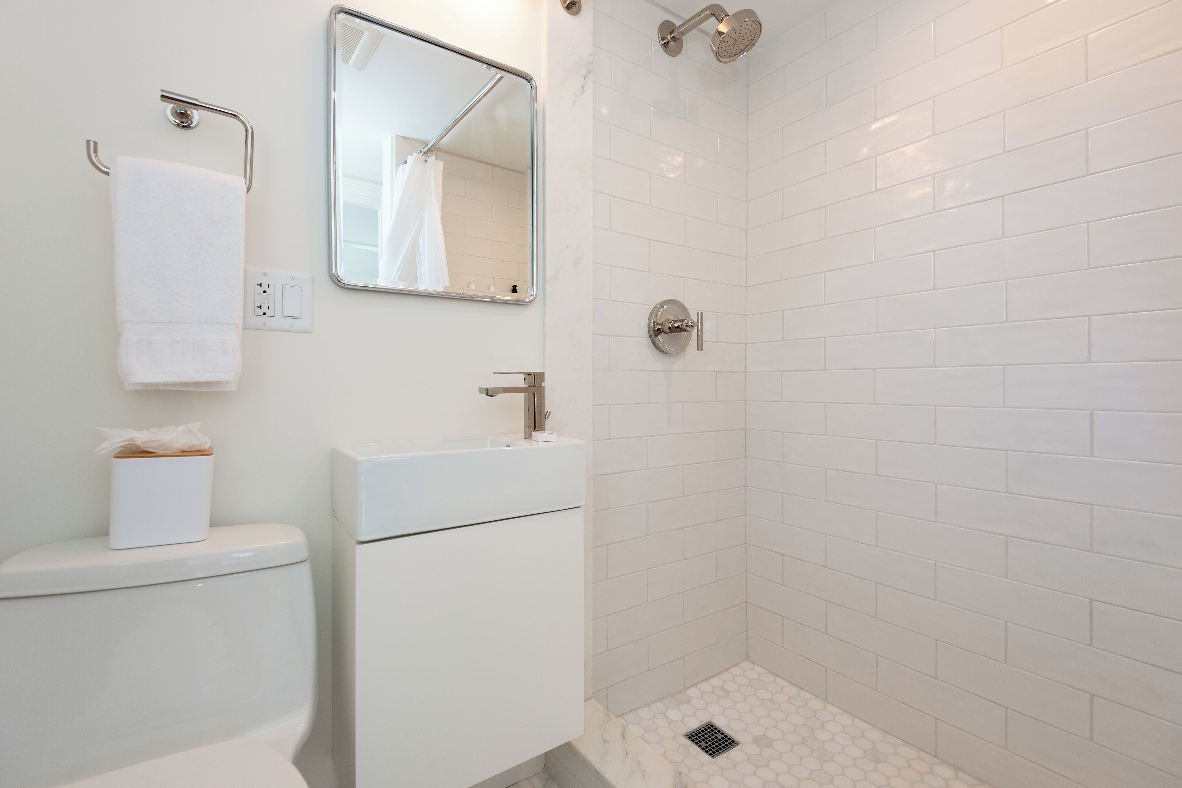 A bathroom with a white sink, mirror, and toilet.