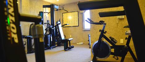 A gym with exercise equipment, a treadmill, and a window providing natural light.