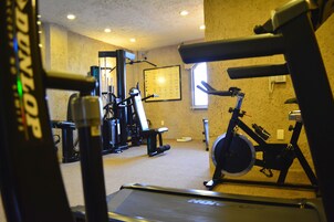 A gym with exercise equipment, a treadmill, and a window providing natural light.