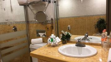 A hotel bathroom with a shower, toilet, sink, and a towel rack.
