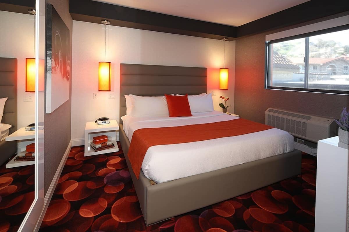 Een hotelkamer met een groot bed, nachtkastjes, een spiegel en een raam.