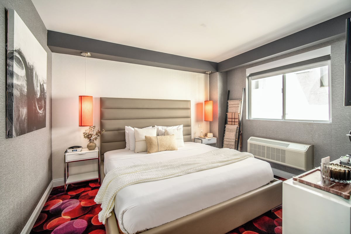 Een moderne hotelkamer met een groot bed, twee nachtkastjes, een radiator en een raam met uitzicht.