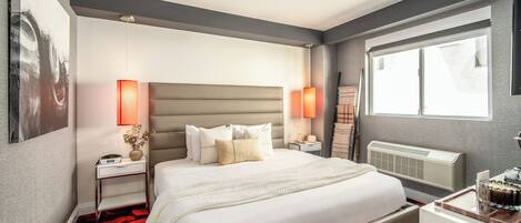 A modern hotel room with a large bed, two bedside tables, a radiator, and a window with a view.