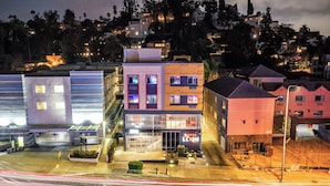 A modern hotel with a prominent entrance, multiple floors, and a parking area. - Lexen Hotel- Hollywood Walk of Fame/Universal Studios (Los Angeles)