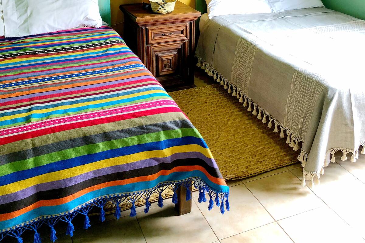 Una habitación con dos camas, una mesita de noche, una lámpara y un cuadro en la pared.