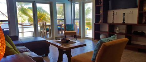 Una habitación con una mesa de madera, dos sofás, una silla, un televisor y una estantería.