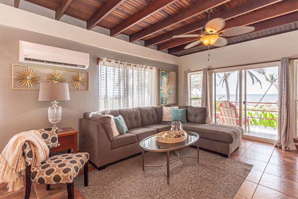 A living room with a sectional sofa, a glass coffee table, and a ceiling fan.