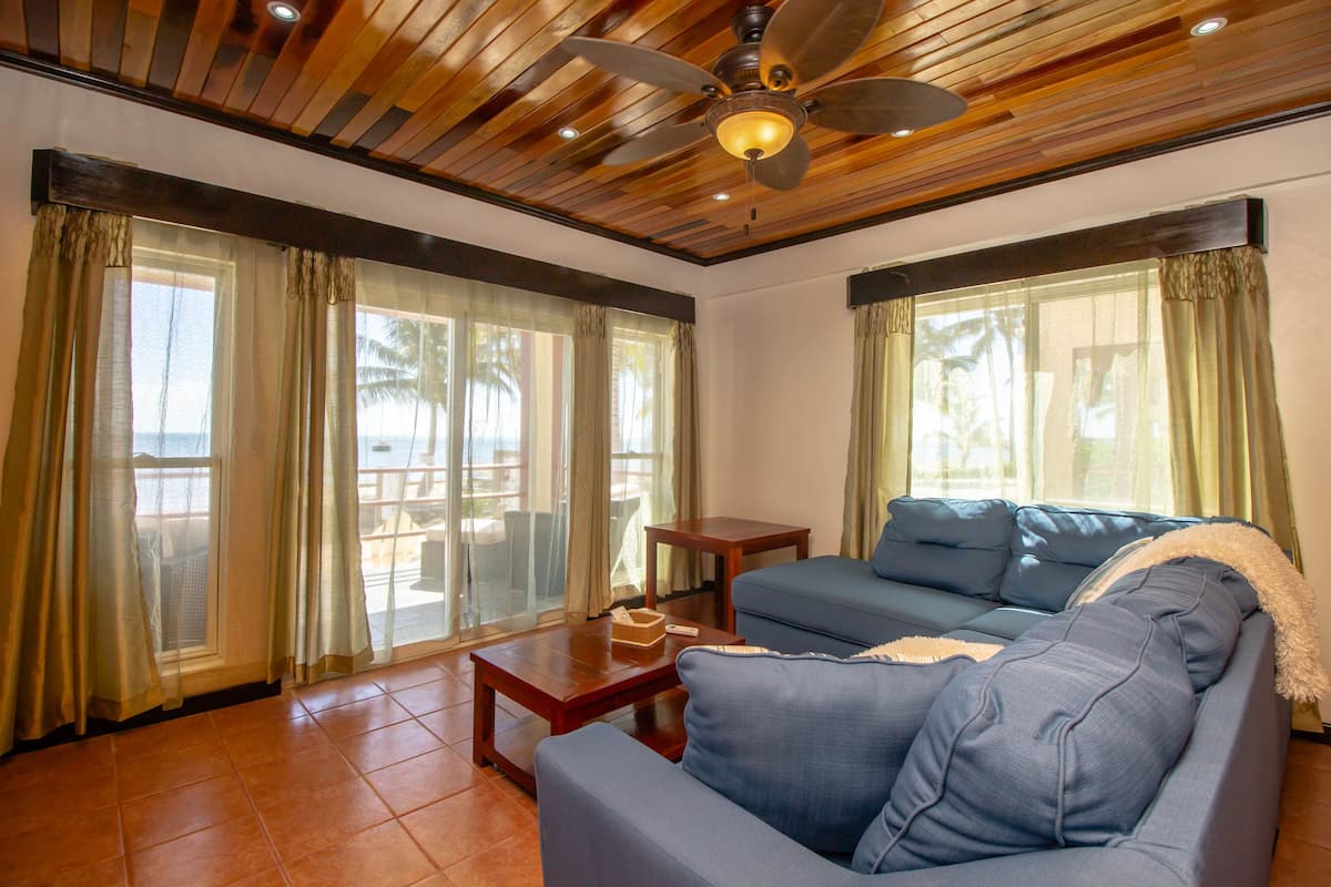 A living room with a blue sofa, a wooden coffee table, and a ceiling fan.