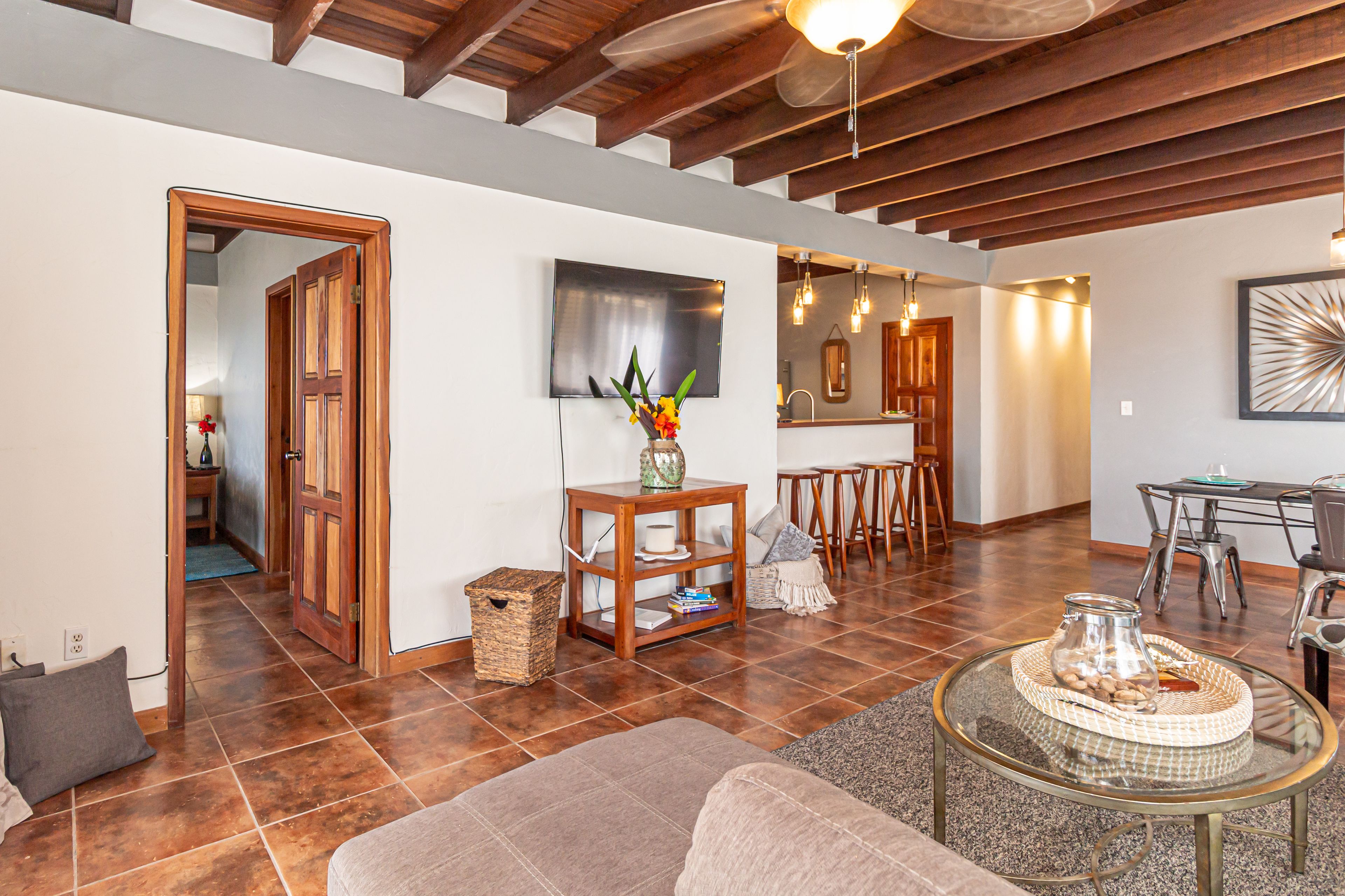 A spacious living area with a wooden ceiling, a glass coffee table, and a cozy seating arrangement.