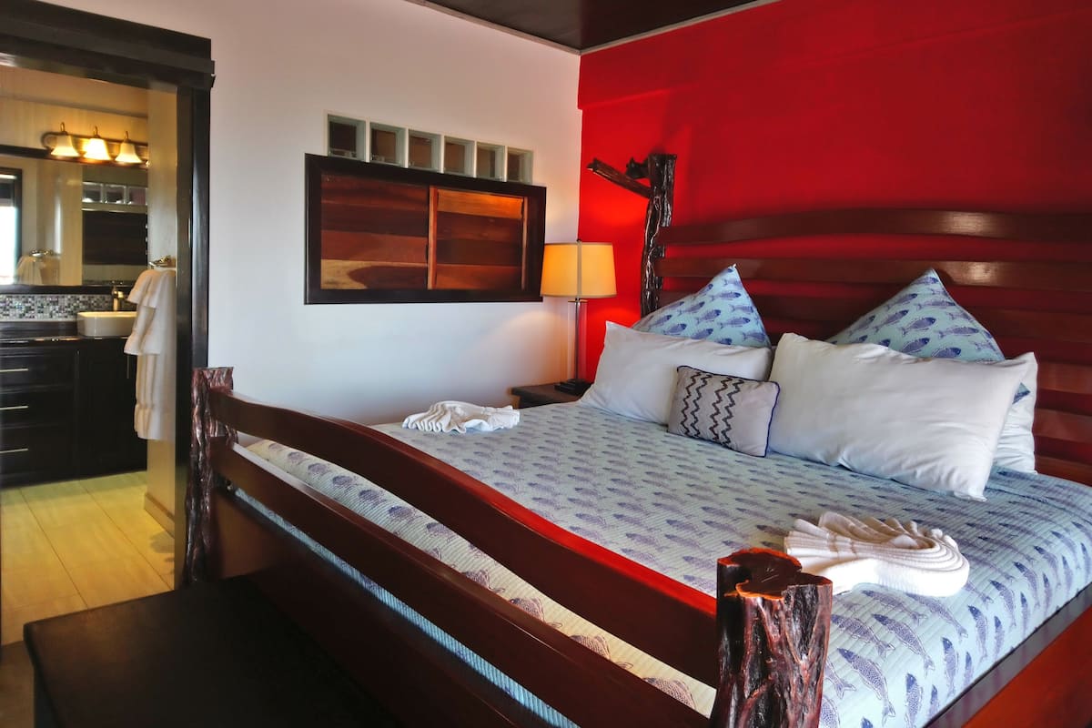 A hotel room with a bed, bedside table, lamp, and a view of the bathroom.