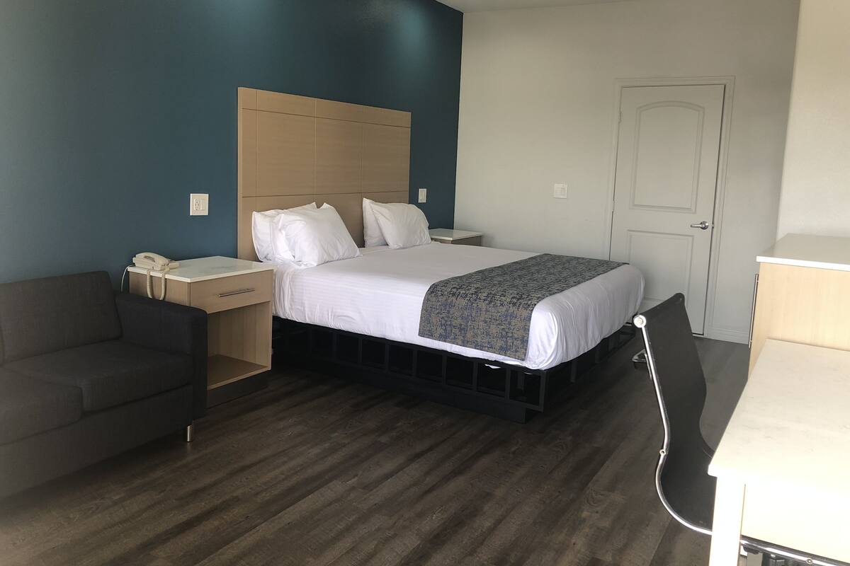 Una camera d'albergo con un letto, un comodino, una sedia e una scrivania con una lampada.