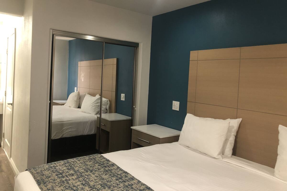 Una camera d'albergo con un letto, un comodino e un armadio con specchio.