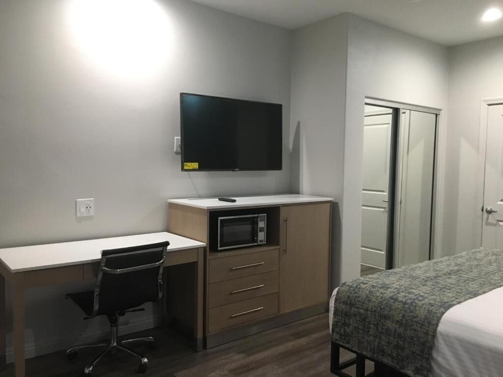A bedroom with a bed, a desk with a chair, a television, and a wardrobe.