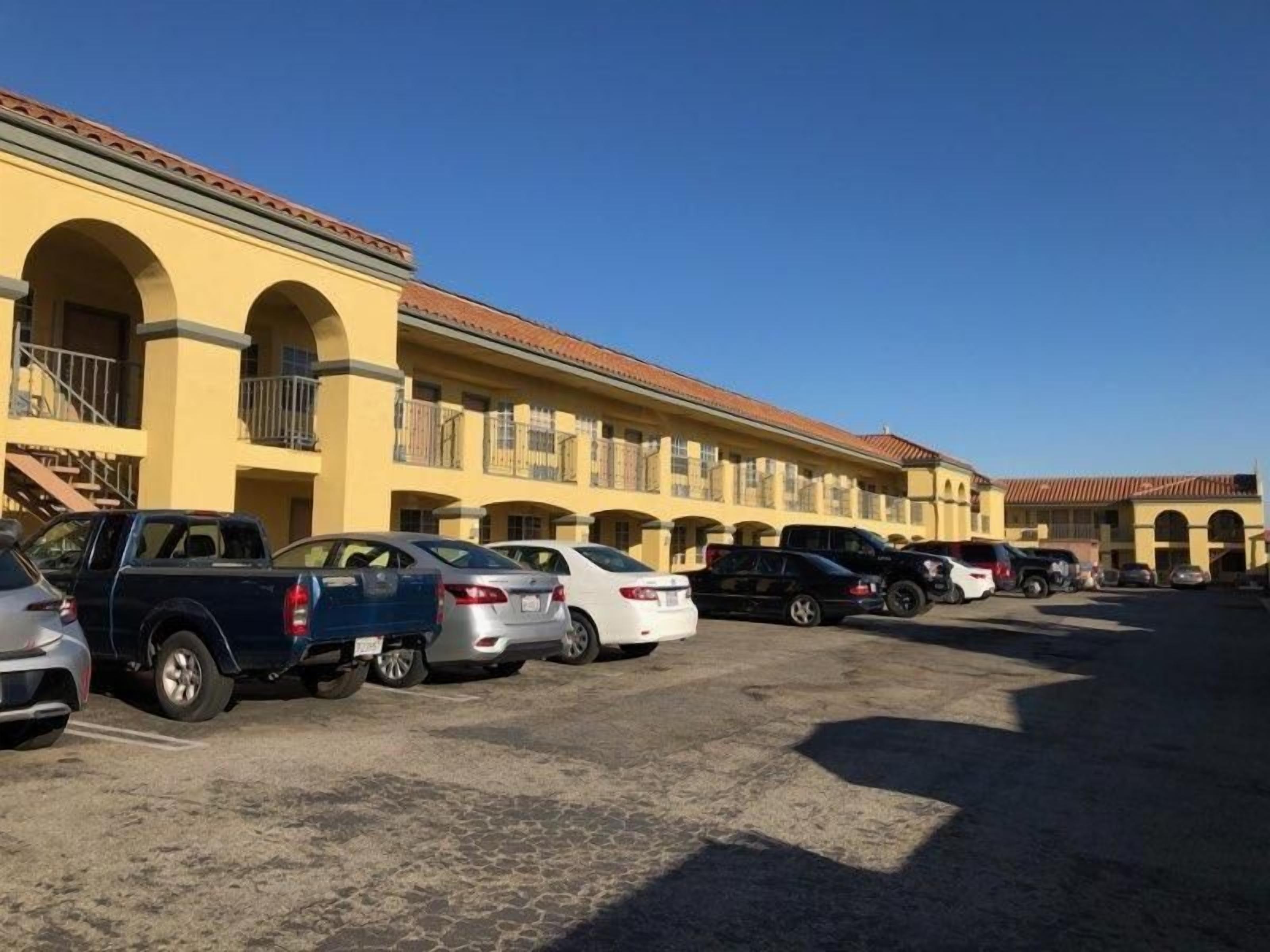 A parking lot with multiple cars and a building with a yellow facade and red roof.