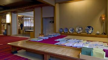 A traditional Japanese room with tatami mats, a wooden table with textiles, and a wall displaying blue and white porcelain plates.
