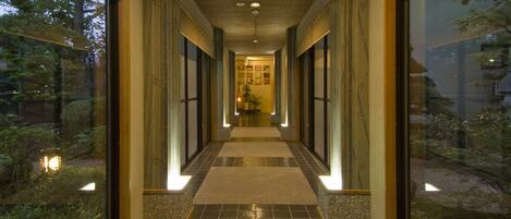 A corridor with a tiled floor, wooden panels, and glass doors leading to a garden.