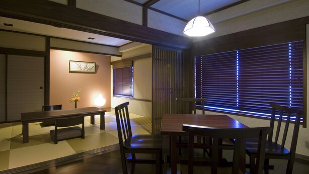 Una habitación tradicional japonesa con suelo de tatami, una mesa baja con sillas y puertas correderas shoji.