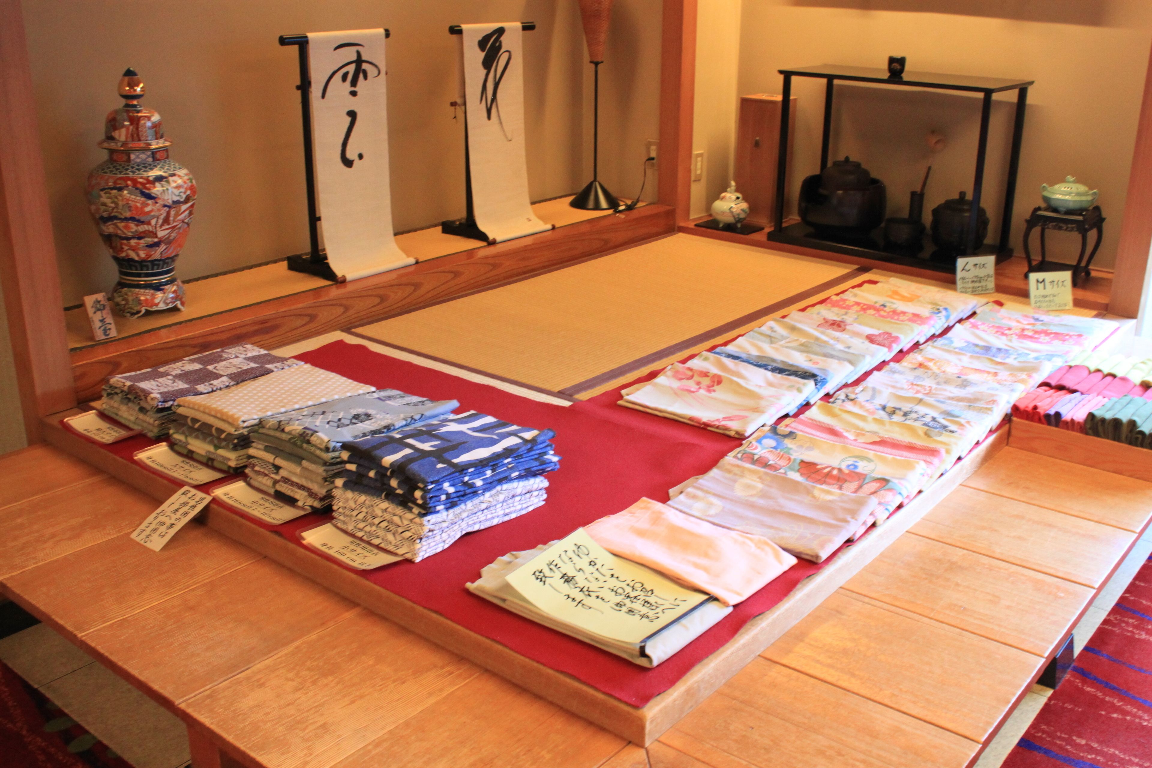 Una exhibición de textiles y cerámica japoneses tradicionales sobre una mesa de madera.