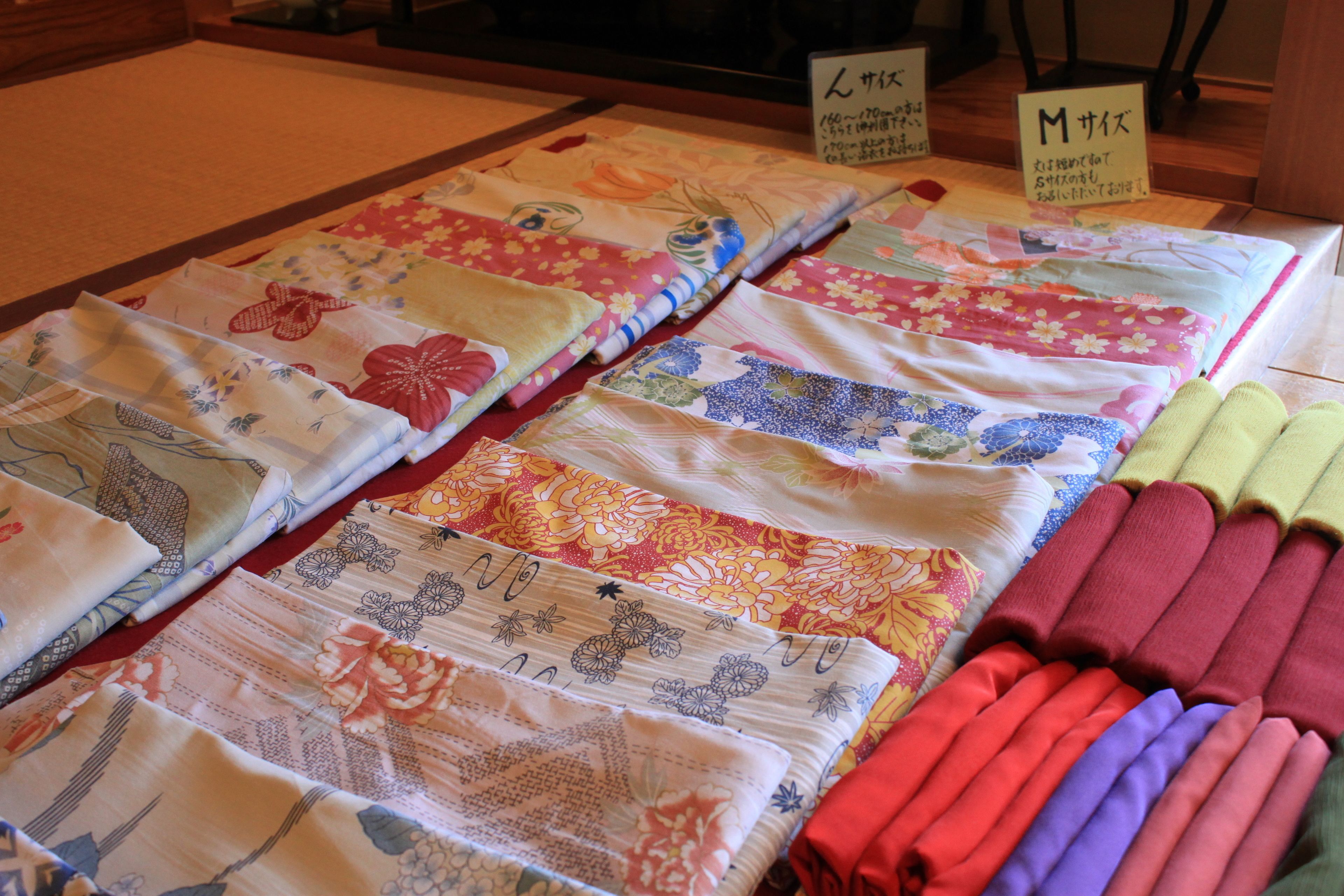 Una exhibición de telas cuidadosamente dobladas con diversos patrones y colores, dispuestas sobre una mesa.