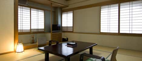 A traditional Japanese room with tatami flooring, a low table, a sofa, and sliding doors.
