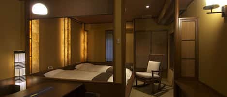 A hotel room with a bed, a chair, a desk, and a small table.