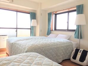 A hotel room with two beds, a massage chair, and large windows with curtains. - Nice Inn Hotel Ichikawa Tokyo Bay (Ichikawa)