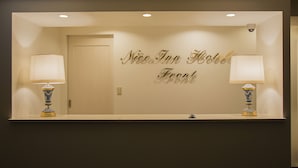 A reception area with a sign reading "Nice Inn Hotel Front" and two lamps on either side. - Nice Inn Hotel Ichikawa Tokyo Bay (Ichikawa)