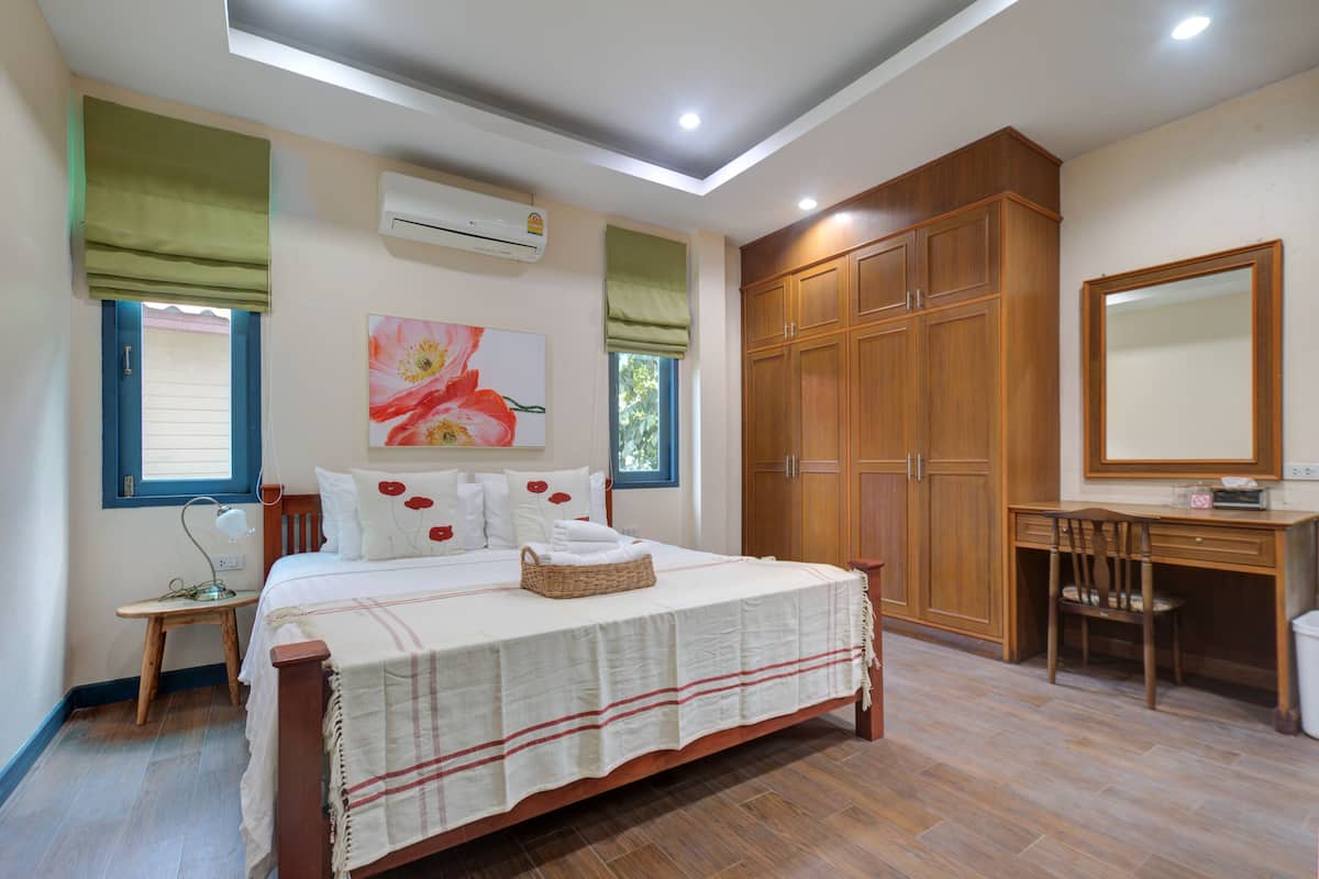 A bedroom with a bed, a desk, and a wardrobe.