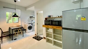 A compact kitchen with a washing machine, a microwave, and a refrigerator. - Baan Patcharintorn Samui (Koh Samui)