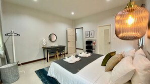 A modern bedroom with a bed, bedside table, and a desk with chairs. - Baan Patcharintorn Samui (Koh Samui)